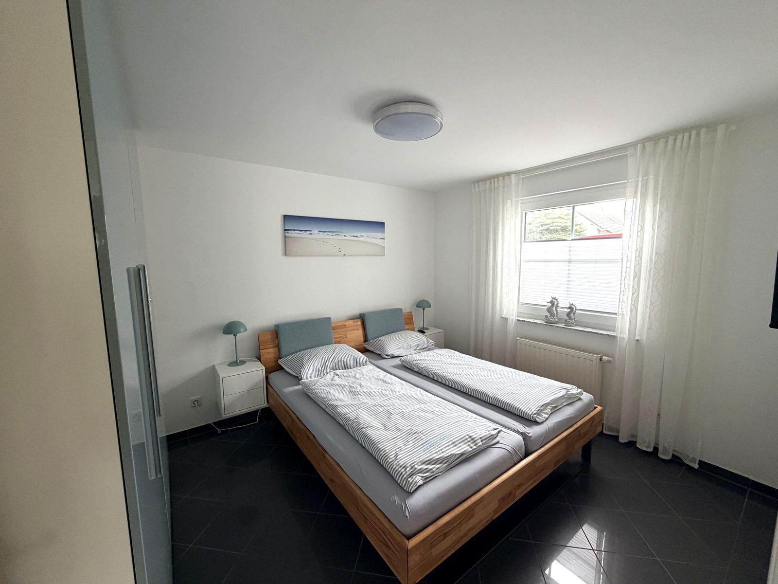 Bedroom with wooden double bed and Baltic Sea picture